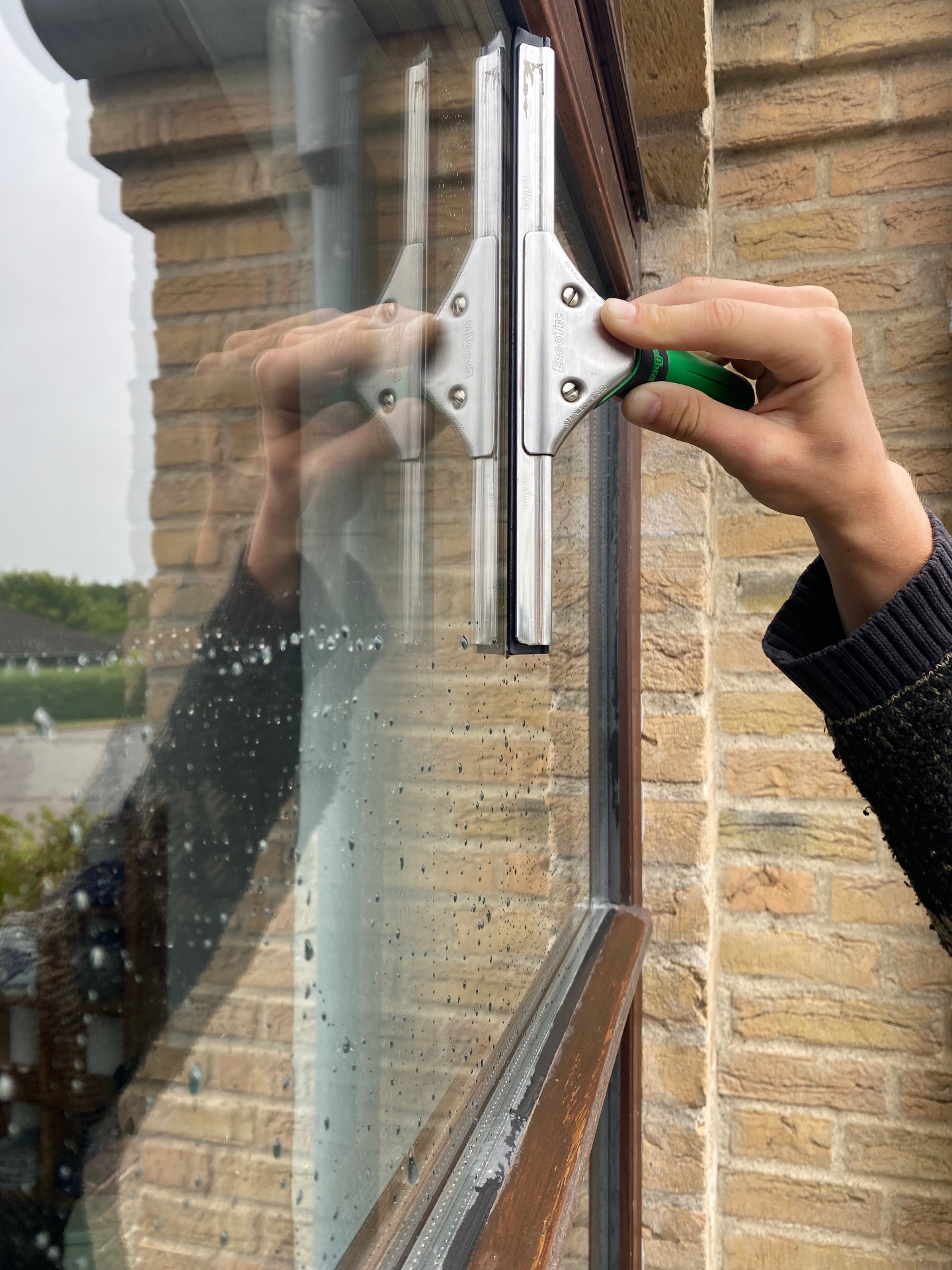 Nærbillede af gummiskraber der pudser et vindue